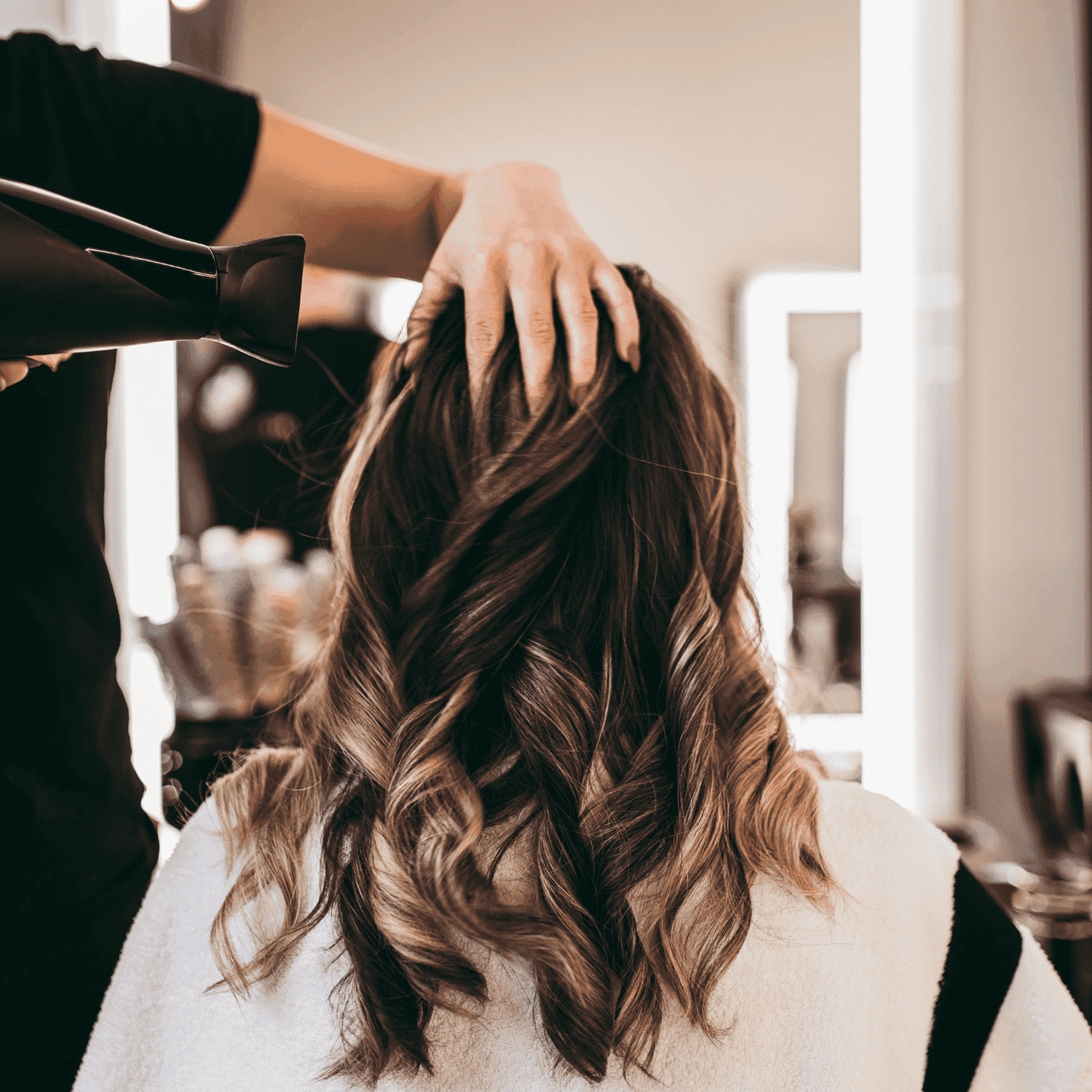 Person having their hair styled with a blow dryer at a salon.