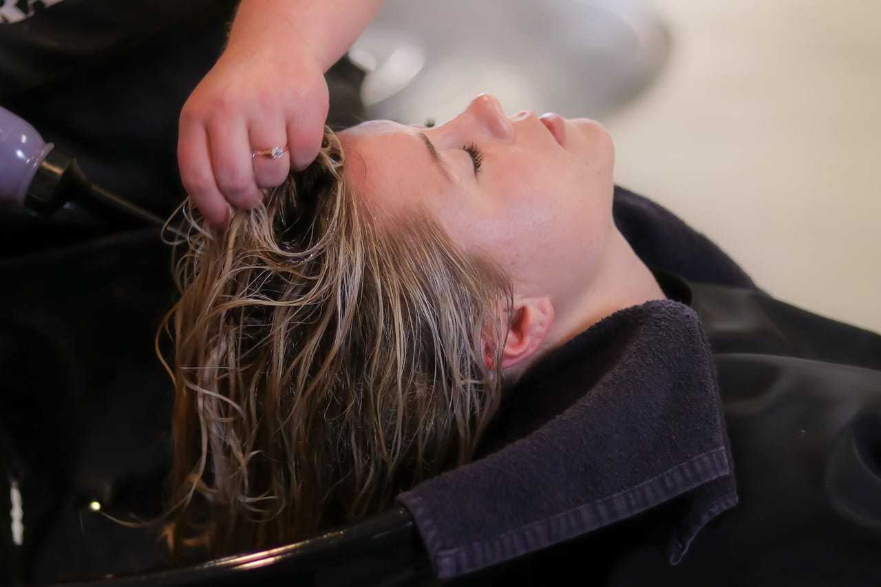 Person getting hair washed at a salon, reclining with eyes closed.