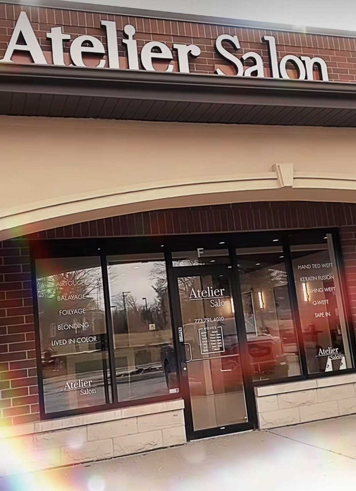 Atelier Salon storefront with glass door and windows displaying services offered.